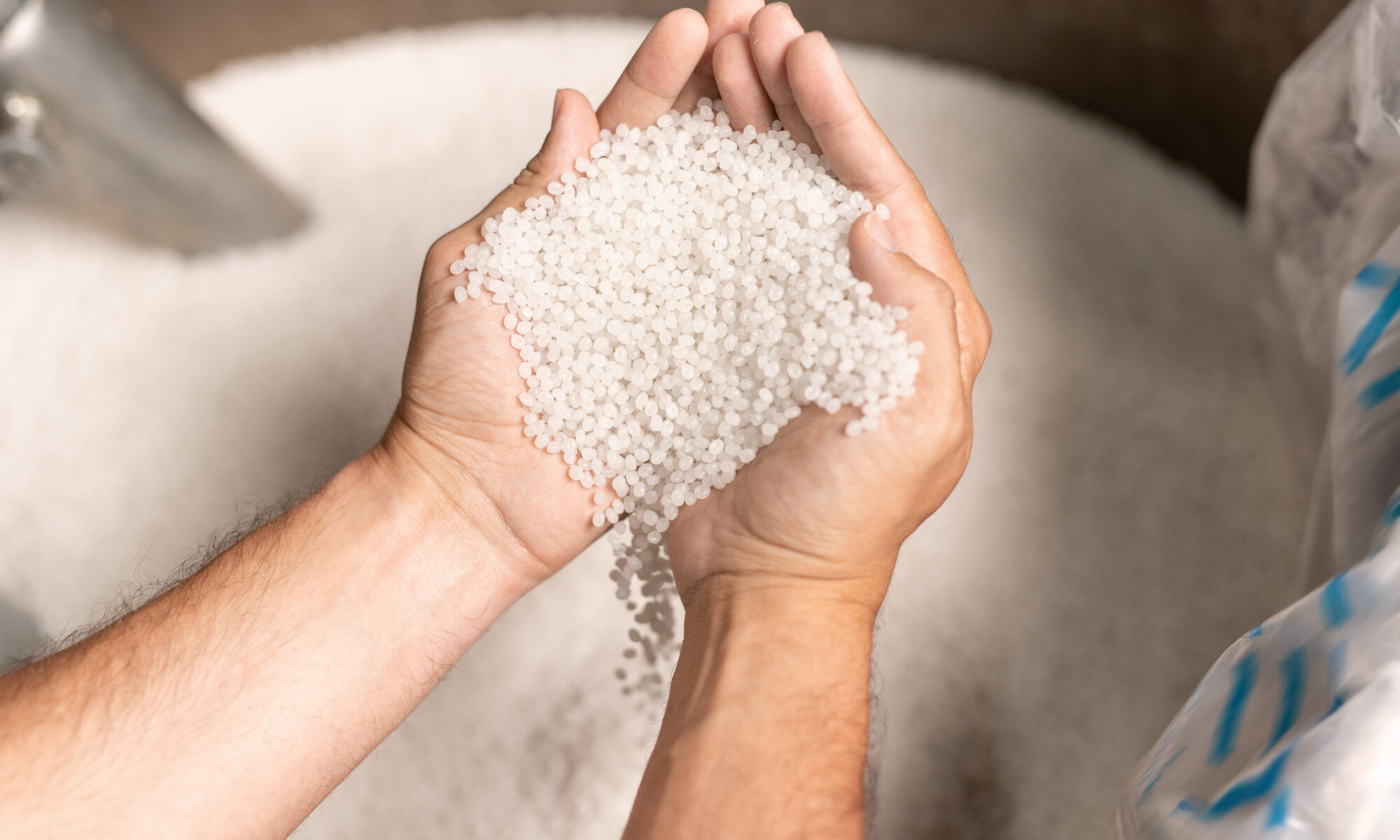 factory worker hands holding pile of white polymer pellets during working process