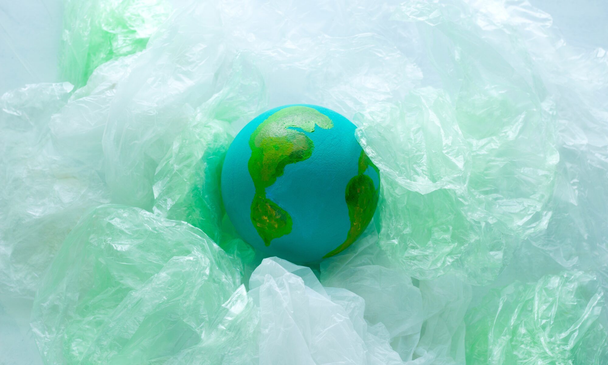 top view of a small model of the Earth planet among plastic bags, environment, global pollution concept, earth day